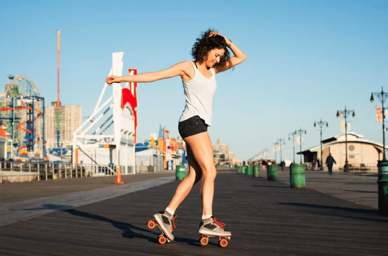 A woman skateboards on a boardwalk, showcasing an eco-friendly transportation option.