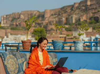 A woman sitting on a couch, focused on her laptop, exploring tips on how to start a blog.