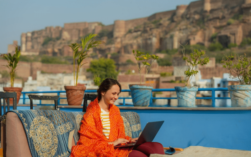 A woman sitting on a couch, focused on her laptop, exploring tips on how to start a blog.