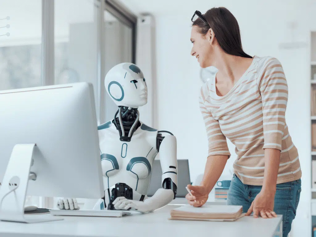 A woman looking at a robot in an indoor setting, surrounded by a wall and various scientific instruments, including a microscope and medical equipment on a desk. She is dressed in casual clothing.