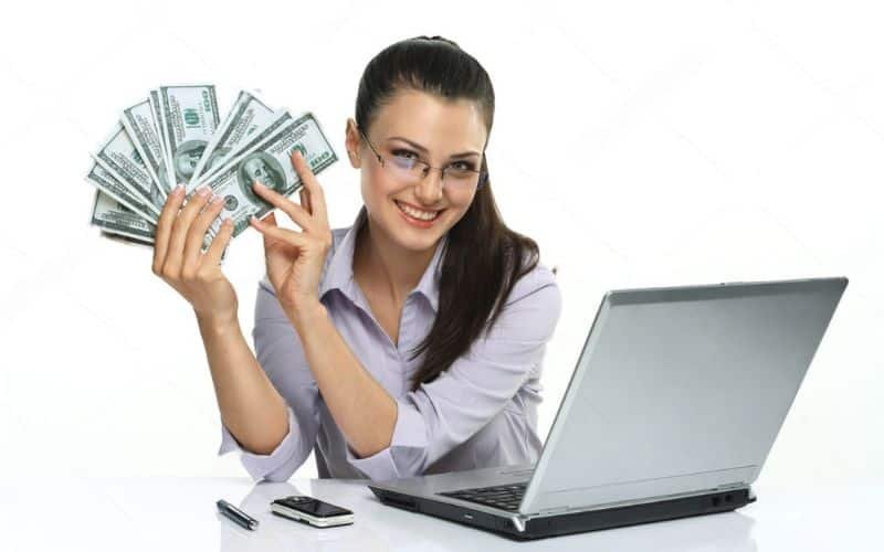 A woman displays cash in front of a laptop, symbolizing success in selling PLR products online.