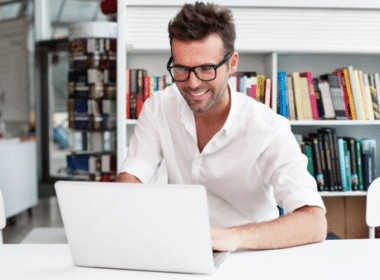 A man with glasses is diligently working on his laptop, showcasing concentration and productivity.