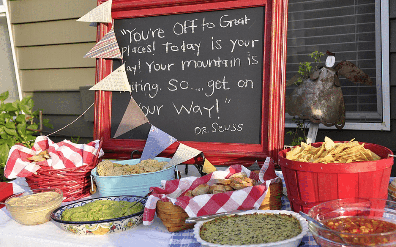 Chalkboard sign reading "You're off to a great day" at a graduation BBQ party, surrounded by festive decorations.