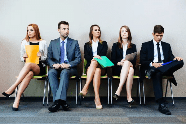 A group of business professionals seated on chairs in an office setting, engaged in discussion or collaboration.