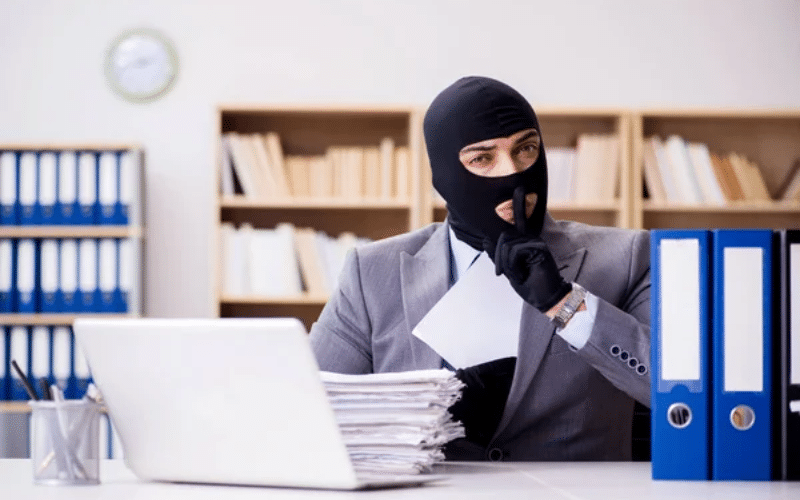 A man wearing a mask sits at a desk, focused on his laptop, with a title reading "The BEST Chat GPT Resume Prompts" nearby.