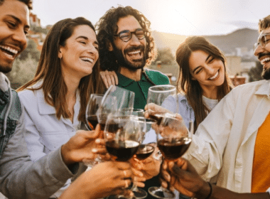A group of friends joyfully toasting with glasses of wine at a casual backyard party.