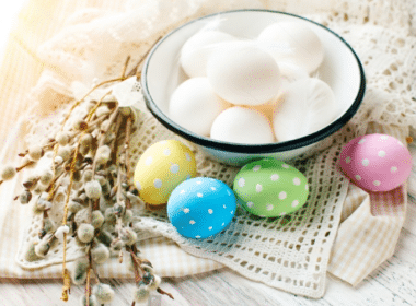 A bowl of colorful Easter eggs sits on a table next to a bowl of milk, showcasing a minimalist Easter theme.