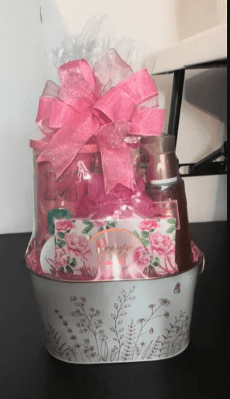 A pink gift basket adorned with a pink ribbon and filled with pink flowers, creating a cheerful and elegant presentation.