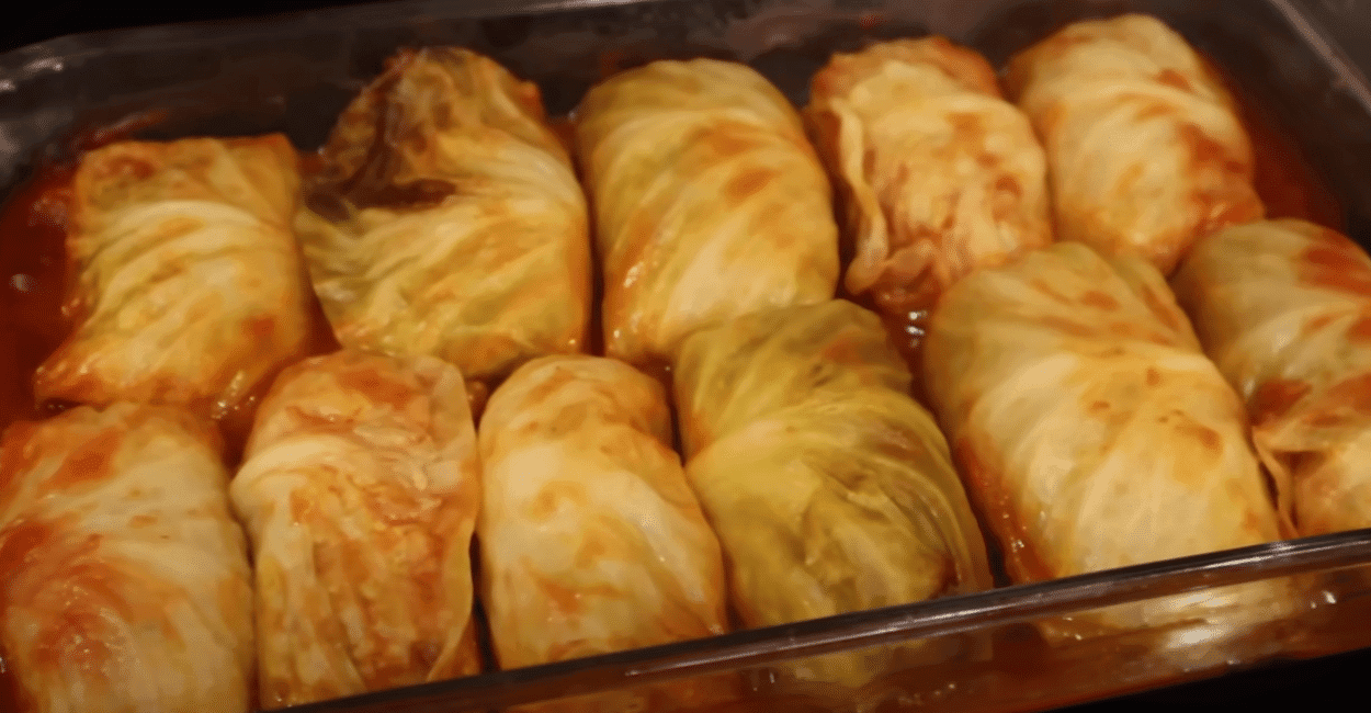 A glass dish filled with neatly rolled stuffed cabbage, highlighting the dish's rich texture and appetizing appearance.