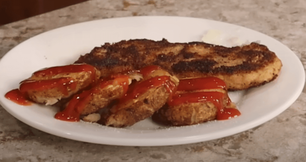 A plate featuring crispy fried chicken pieces accompanied by a small bowl of ketchup.