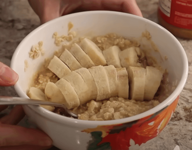 A bowl of oatmeal topped with sliced bananas and a dollop of peanut butter.
