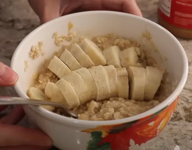A bowl of oatmeal topped with sliced bananas and a dollop of peanut butter.