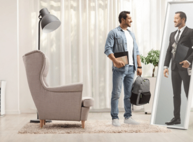 A man stands in front of a mirror, holding a suitcase, reflecting on his smart money habits.