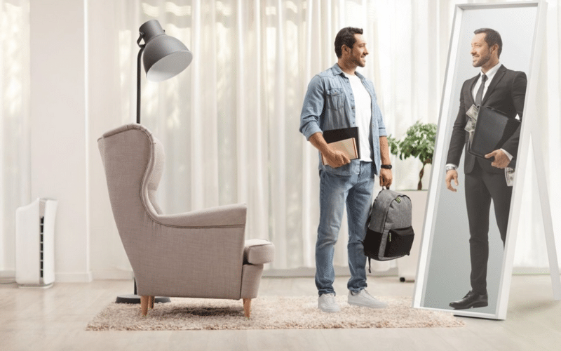 A man stands in front of a mirror, holding a suitcase, reflecting on his smart money habits.