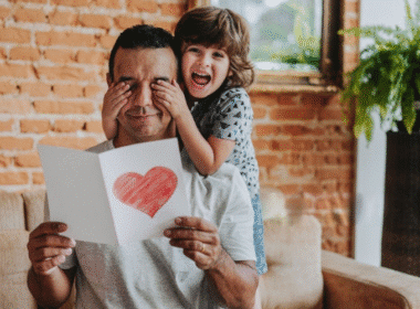 Father and son proudly hold a heart-shaped paper, showcasing a heartfelt DIY Father’s Day gift idea.