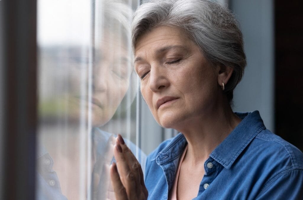 . An older woman gazes thoughtfully out the window, reflecting on life and the theme of "Flip the Regret Script."