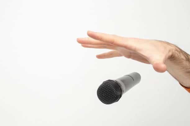 A hand reaching for a microphone against a white background, representing 'The Broke Girl’s Mic Drop' theme.