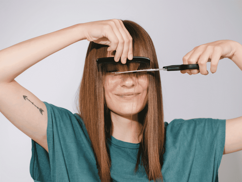 A woman is cutting her hair with scissors, embodying the idea of treating her hair like royalty.
