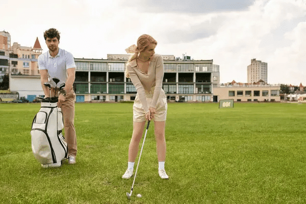 A man and woman play golf on a lush green field, embodying the theme of manual labor as therapy.