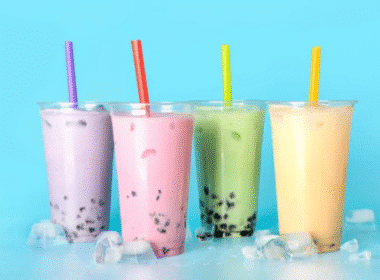 Four colorful bubble tea drinks in glasses on a blue background, showcasing vibrant flavors for a food marketing concept.