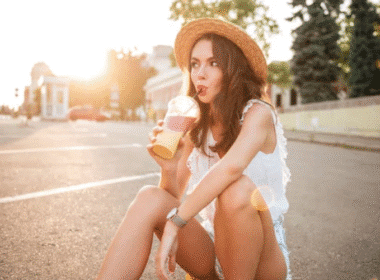 A woman sitting on the street, enjoying a homemade nonalcoholic drink.