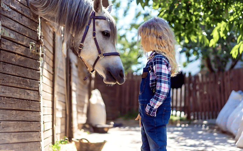 A little girl poses next to a horse, representing the enriching experiences of working with animals in various jobs.