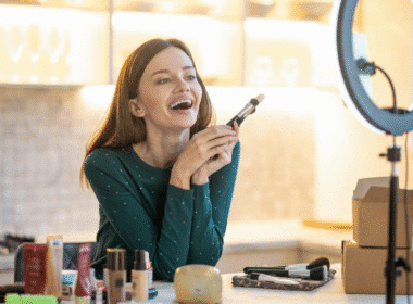 A smiling woman holds a makeup brush, embodying beauty and confidence for a beauty blog concept.
