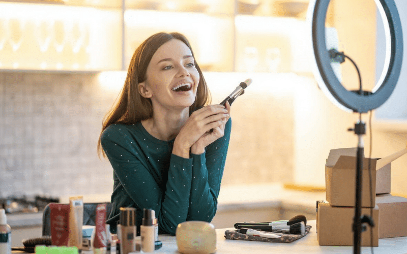 A smiling woman holds a makeup brush, embodying beauty and confidence for a beauty blog concept.