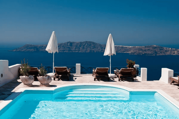 A tranquil swimming pool overlooking the sea and mountains, capturing the beauty of a Greek island like Crete or Paros.