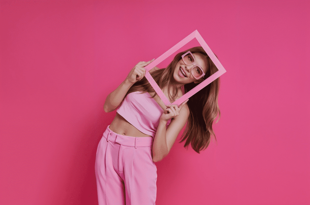 A woman in pink holds a frame against a pink background, illustrating tips for filming lifestyle content.