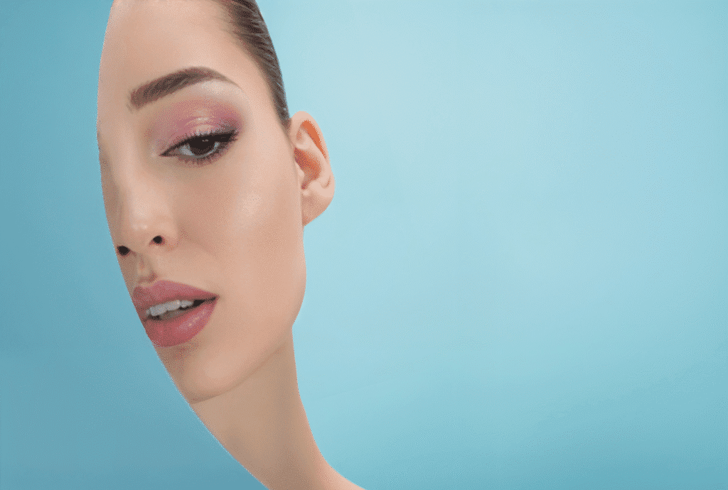 Beautiful woman with blue eyes and pink lips, promoting a DIY setting spray for makeup longevity.