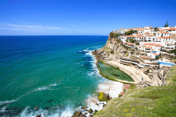 Scenic view of Portugal's coastline featuring white houses along the shore and vibrant blue water.