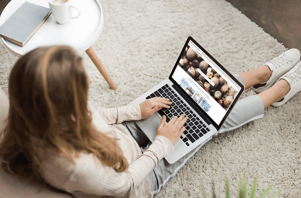 A woman sitting on the floor, focused on her laptop, exploring ideas for starting a faceless YouTube channel.