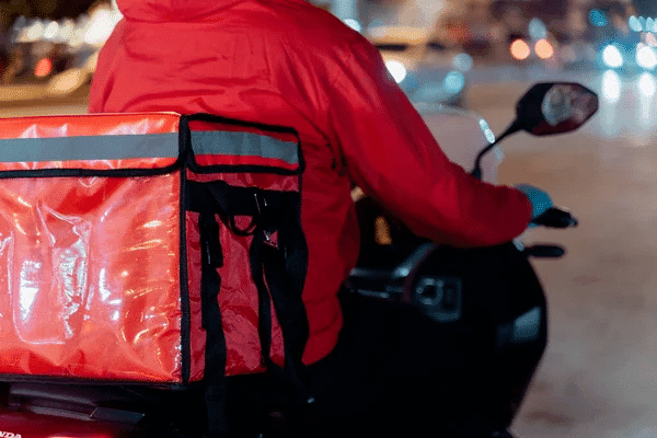 A delivery man on a motorcycle carrying a red bag, promoting Smart “On the Way” Orders service.