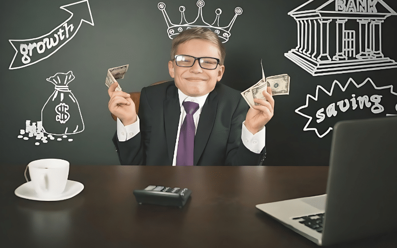 A man in a suit sits at a desk with money and a laptop, illustrating a lesson on teaching kids about money management.