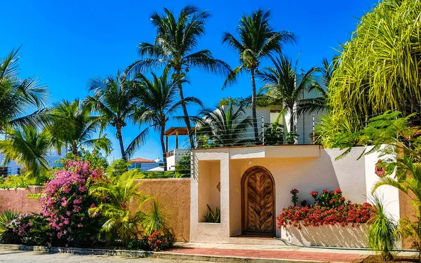 A stunning tropical home in Tulum, Mexico, surrounded by palm trees and vibrant flowers.