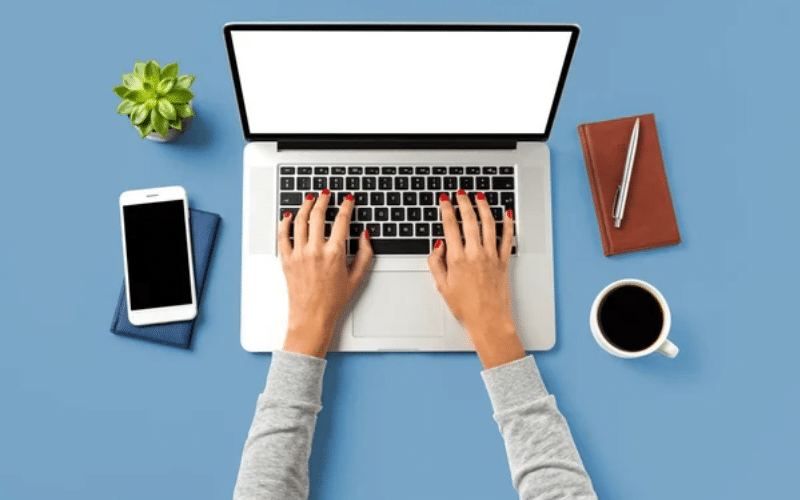 Top view of a woman's hands typing on a laptop with a blank screen, suggesting opportunities for fast typers.