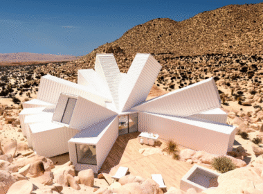 A white house in the desert surrounded by rocks, showcasing a DIY shipping container home in a rugged landscape.