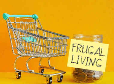 Shopping cart filled with coins on a yellow background, illustrating the concept of frugal grocery shopping.