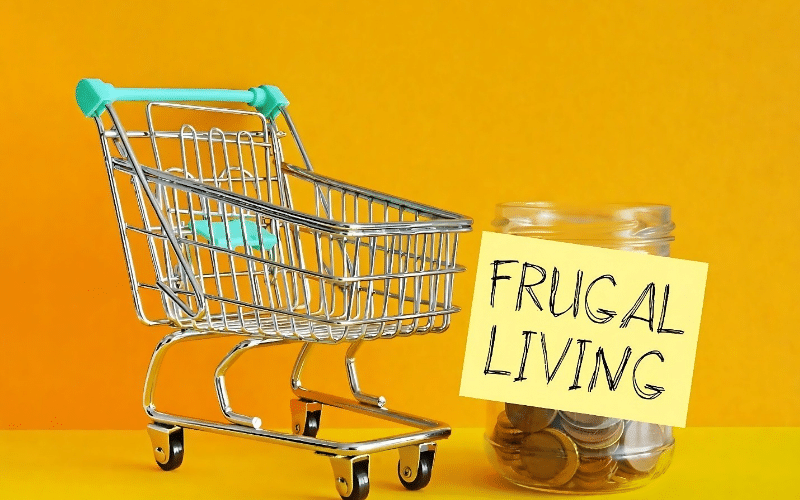 Shopping cart filled with coins on a yellow background, illustrating the concept of frugal grocery shopping.