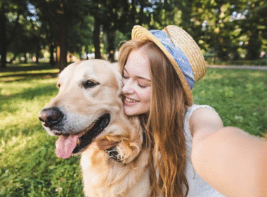 A woman smiles while taking a selfie with her dog, showcasing a joyful moment for her pet sitting business names.