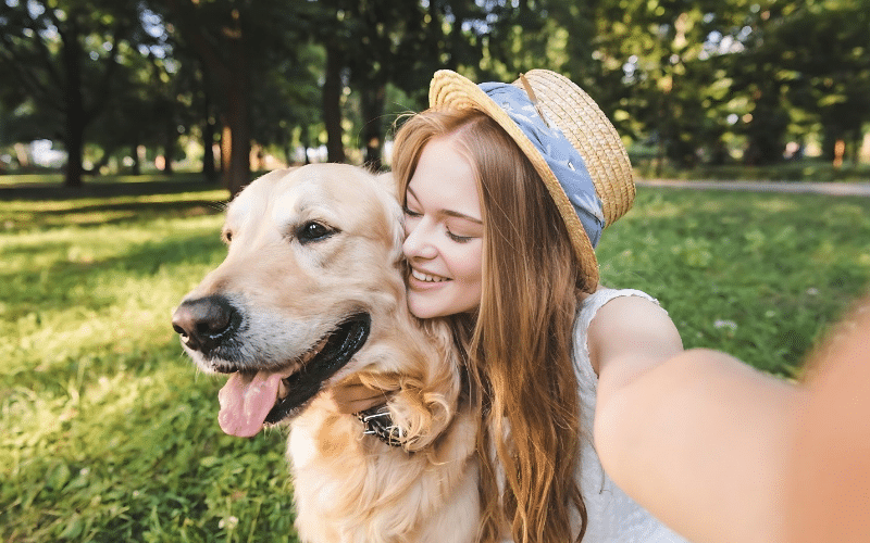 A woman smiles while taking a selfie with her dog, showcasing a joyful moment for her pet sitting business names.