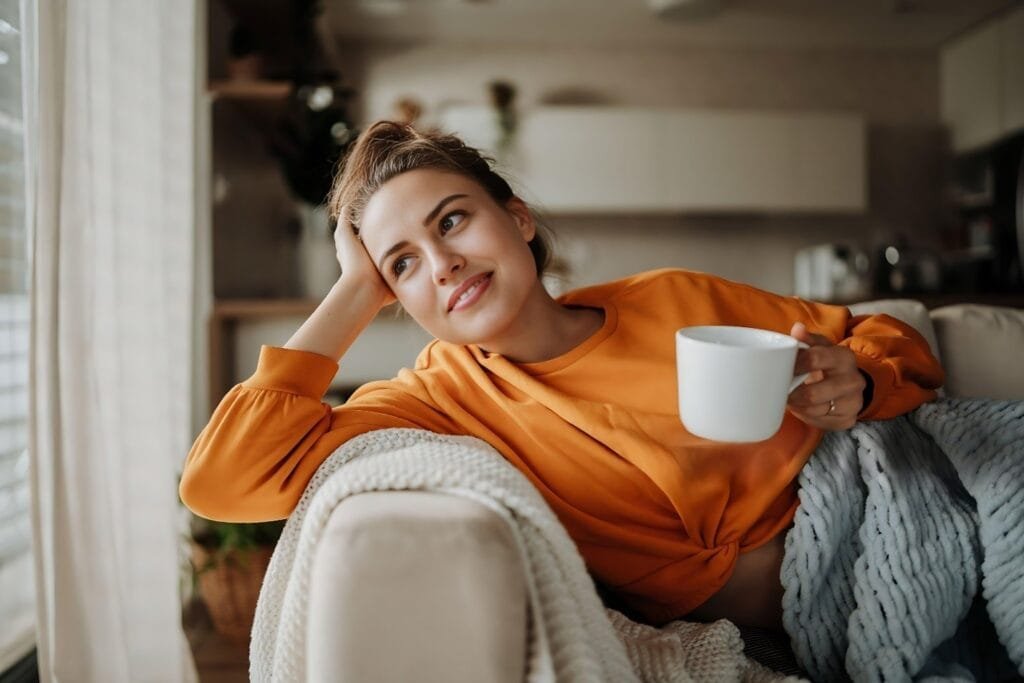 A woman relaxes on a couch, sipping coffee during a Wellness Reset Weekend event.