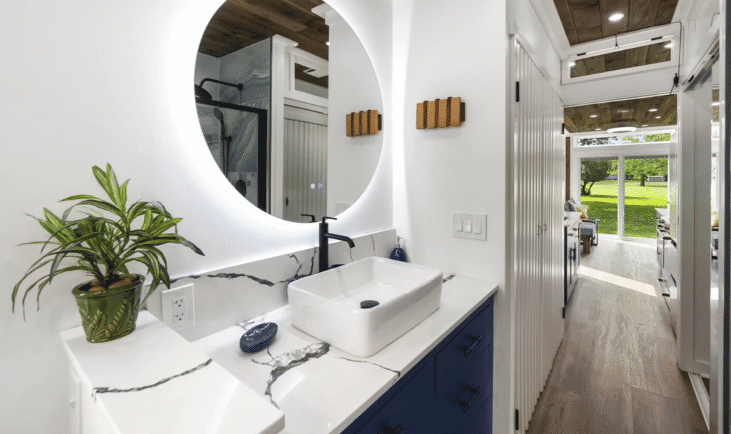 A stylish bathroom featuring a round mirror above a modern sink, showcasing a clean and contemporary design.