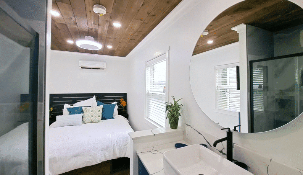 A bright bathroom featuring a white bed and a round mirror reflecting the room's light and decor.