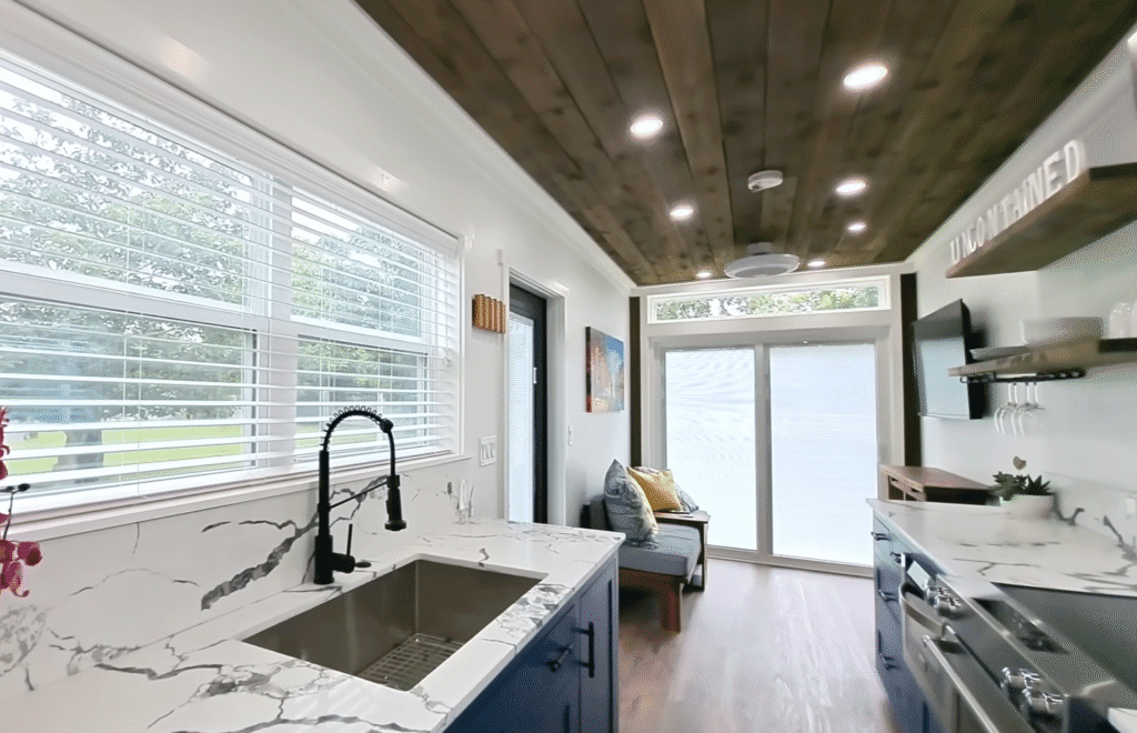A bright, tidy tiny house kitchen with white cabinetry and a sleek, contemporary aesthetic.