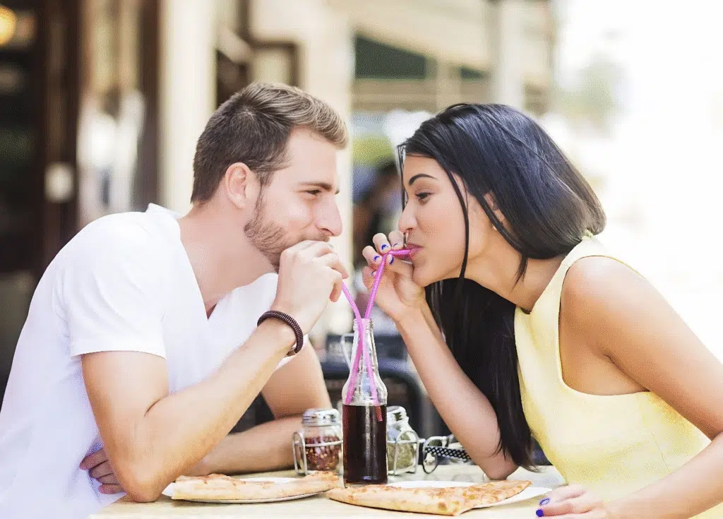 A man and woman enjoy pizza together at a table, representing a fun and affordable date idea for couples.