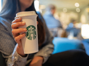 A woman holding a Starbucks cup, showcasing the cheapest drink option available at the coffee shop.