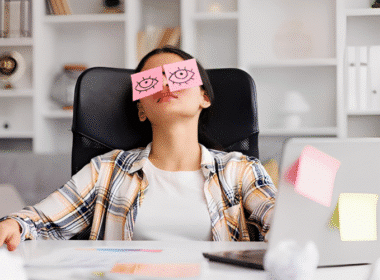 A woman with a smile sits at her desk, embodying the concept of 'Lazy Girl Jobs' in a relaxed work environment.