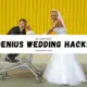 A bride and groom joyfully push a shopping cart labeled "Genius Wedding Hacks" during their wedding planning.